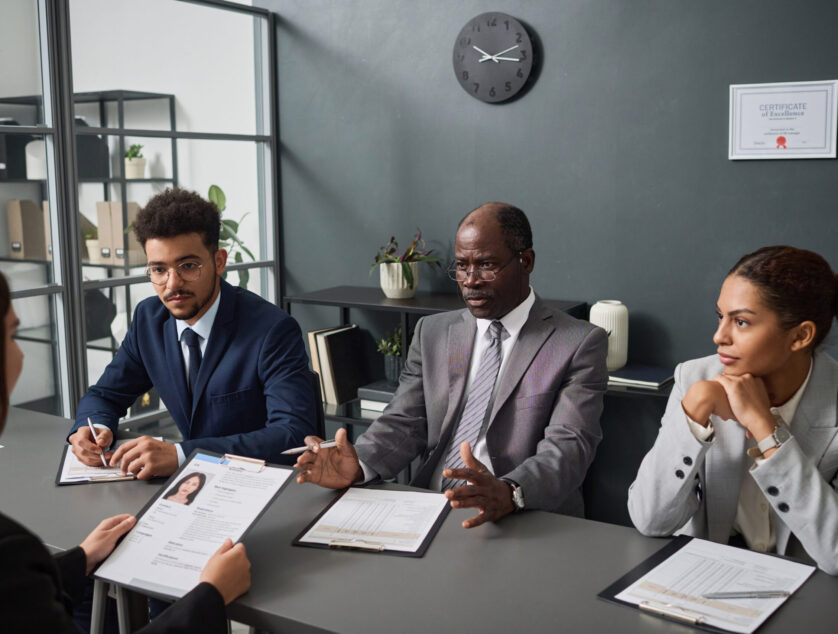 Group of specialists asking questions to applicant during interview for getting visa in office